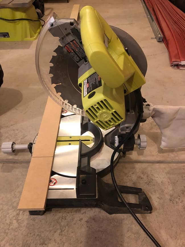 Use a miter saw to cut custom lengths of the MDF strips for the DIY accent wall. 