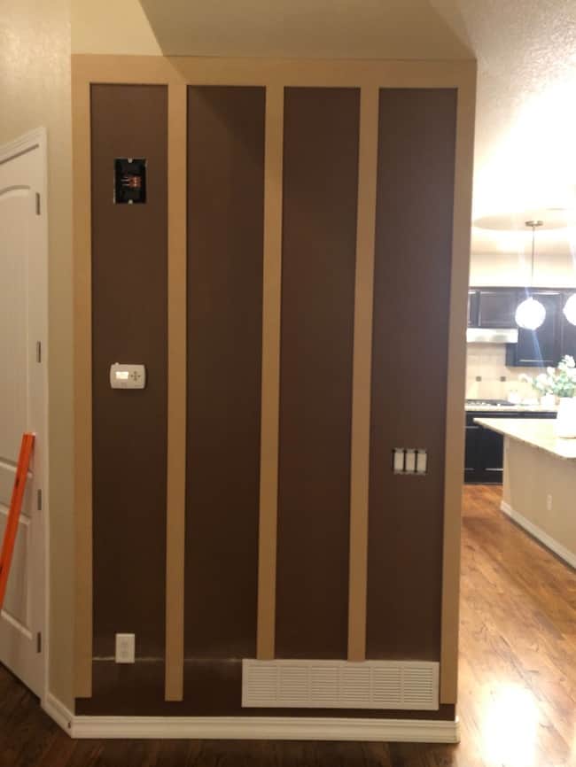After putting up all the hardboard panels and MDF strips, it's time to caulk the edges. This DIY Vertical Paneled Accent Wall is coming together!