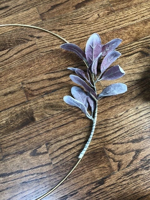 Use floral wire to secure the purple lambs ear to the gold hoop. 