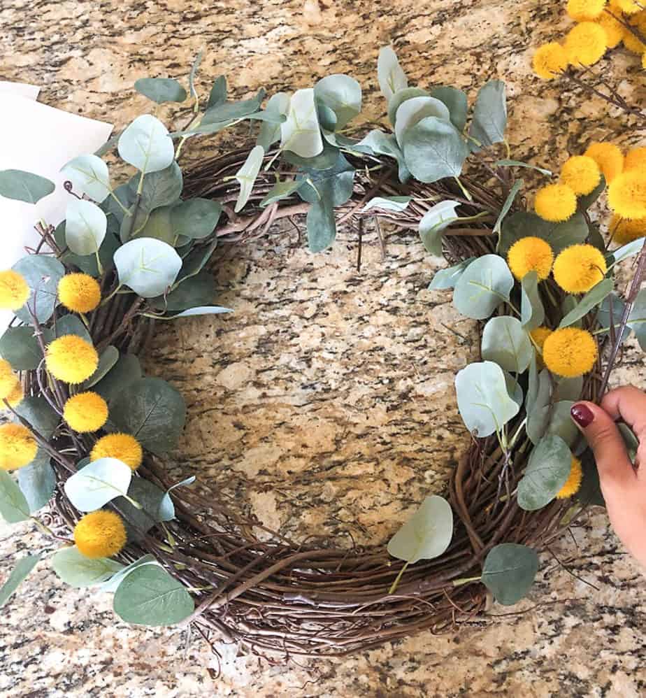 Lay the yellow flower balls over the eucalyptus to add texture and color to your fall wreath. 