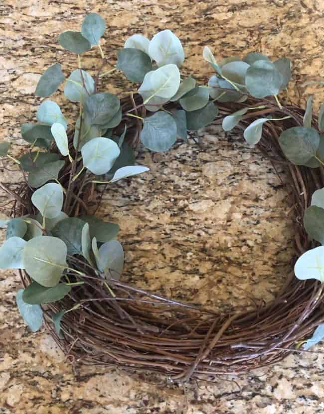 Place the eucalyptus stems around the grapevine wreath first. 