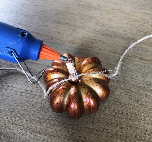 Use your hot glue gun to glue your pumpkins to the twine. 