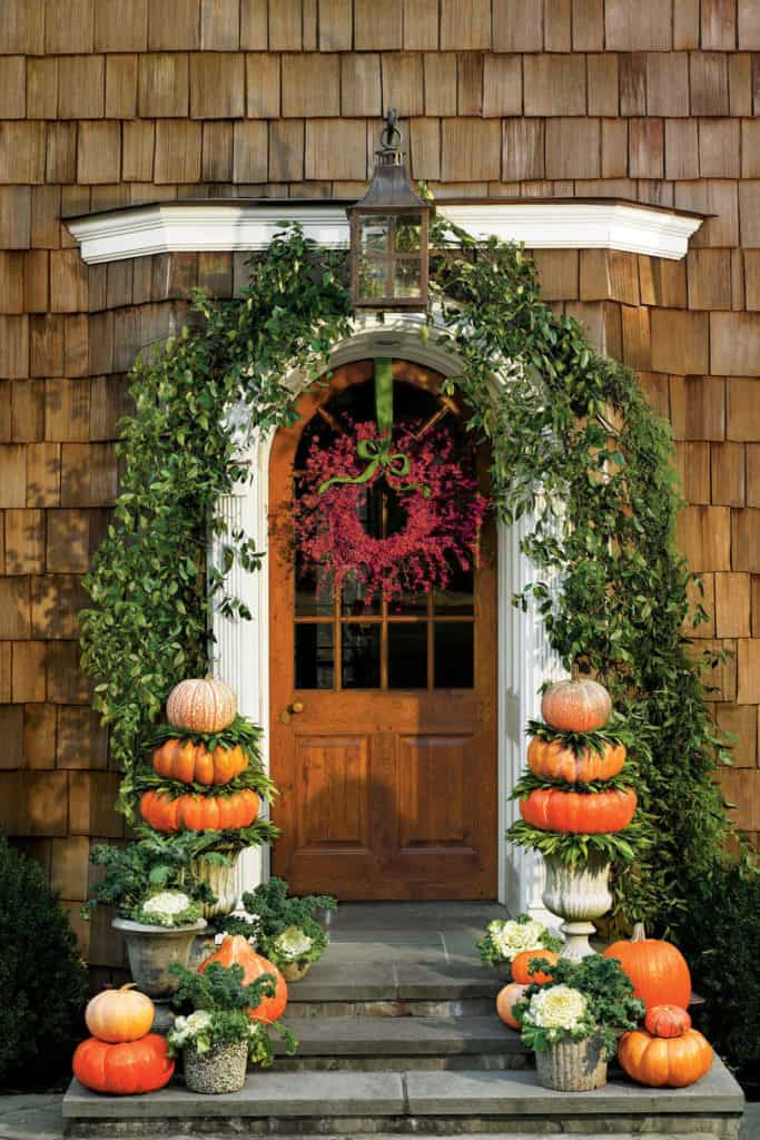 Stack pumpkins on planters with cabbage and kale for your fall porch decorations. 