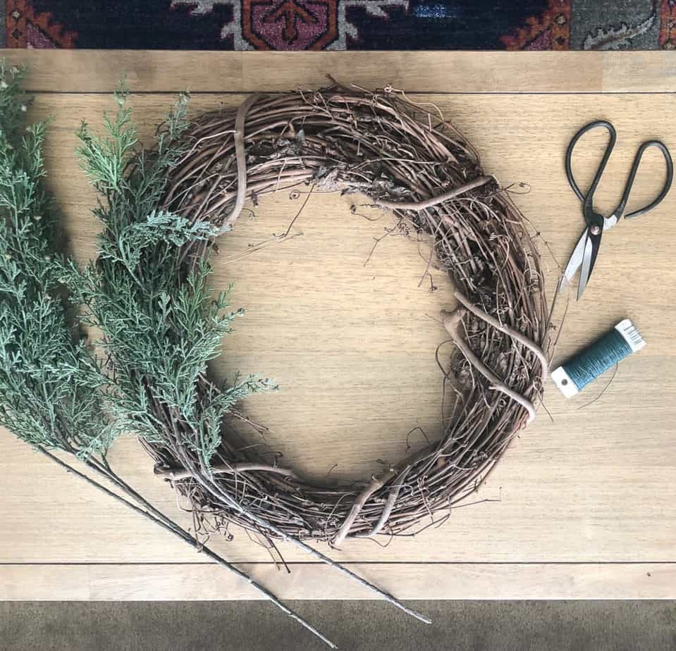 Attach 5 faux pine stems to the 18" grapevine wreath with floral wire. 