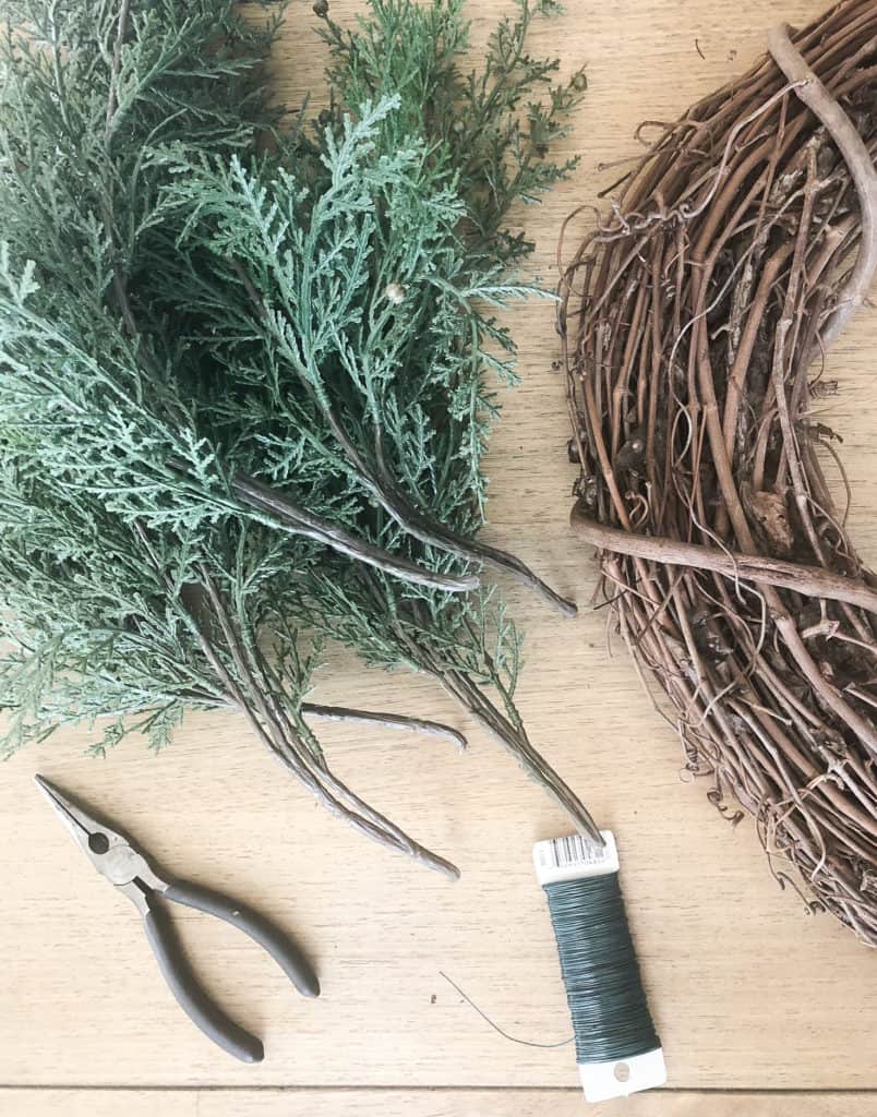 Use a wire cutter to cut the faux pine stems and floral wire to attach them to the Christmas wreath. 