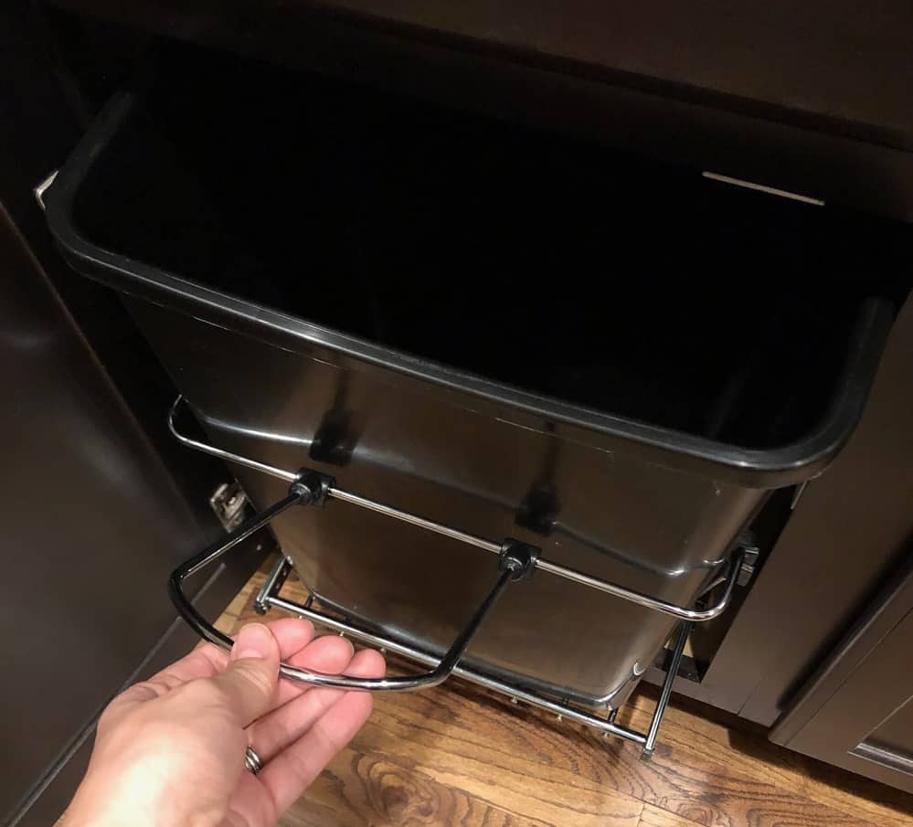 It has a handle to pull your trash can out. You can also buy a door mounting kit, if you want it to attach to your cabinet door. 